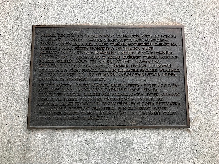 Pomnik Katyński w Jersey City w stanie New Jersey nad rzeką Hudson jest według notatki w Wikipedii pierwszym pomnikiem katyńskim w Stanach Zjednoczonych. Odsłonięto go w maju 1991 roku. Unikam takich rzeczy, ale tym razem nie mam wyjścia i muszę posiłkować się informacjami z tego portalu. Z notatki z Wikipedii wynika że : „Autorem monumentu upamiętniającego ofiary zbrodni katyńskiej popełnionej w 1940 roku przez radziecką policję polityczną NKWD na polskich jeńcach wojennych na plecenie Biura Politycznego KC WKP, jest polski rzeźbiarz Andrzej Pityński. Pomnik o wysokości około 12 metrów składa się z granitowego cokołu o wadze 120 ton, na którym znajduje się wykonana z brązu postać zakneblowanego żołnierza z rękoma związanymi z tyłu, z wbitym w plecy bagnetem nasadzonym na karabin. Rzeźba żołnierza ma wagę 6 ton”. Pomnik usytuowany jest w pięknej scenerii, w tle rozpościera się panorama Manhattanu. Część Jersey City, w której się znajduje przechodzi od kilku lat zmiany a ich efektem jest nowoczesny, ciągnący się na kilka kilometrów deptak wzdłuż rzeki Hudson z widokiem na wieżowce Nowego Jorku. Pan X i ja nocowaliśmy kilka razy w tej okolicy w czasie naszych wypadów do Nowego Jorku, ponieważ można dostać się stąd na Manhattan w kilka minut za pomocą promów. Wielkim plusem nocowania po tej stronie rzeki są widoki i zdjęcia jakie można tu zrobić. O tym jak doszło do tego, że w New Jersey stanął Pomnik Katyński można przeczytać na tablicy znajdującej się na cokole : Na Pomniku Katyńskim znajduje się również pamiątkowa tablica upamiętniająca zamachy z 11 września. Wmurowano ją tutaj we wrześniu 2004 roku :